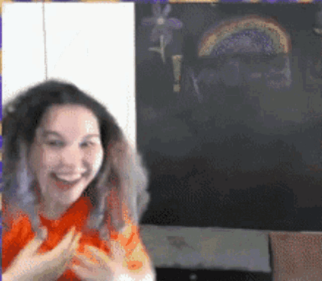 a woman is smiling in front of a chalkboard with a rainbow on it