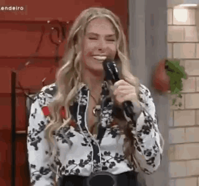 a woman is smiling while holding a microphone .