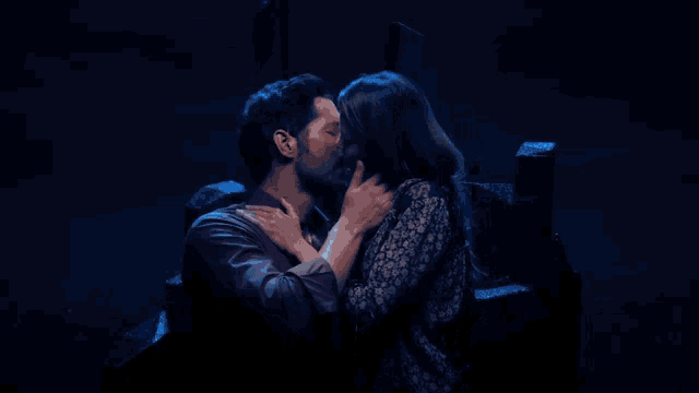 a man and a woman are kissing in the dark