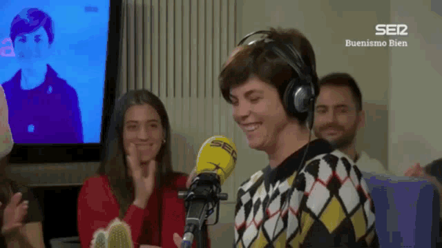 a woman wearing headphones is smiling in front of a microphone that says ser on it