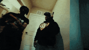 a man wearing a hoodie with the letter b on it stands next to another man