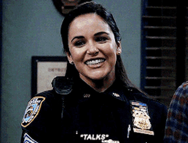 a woman in a police uniform is smiling with the words " talks " on her chest