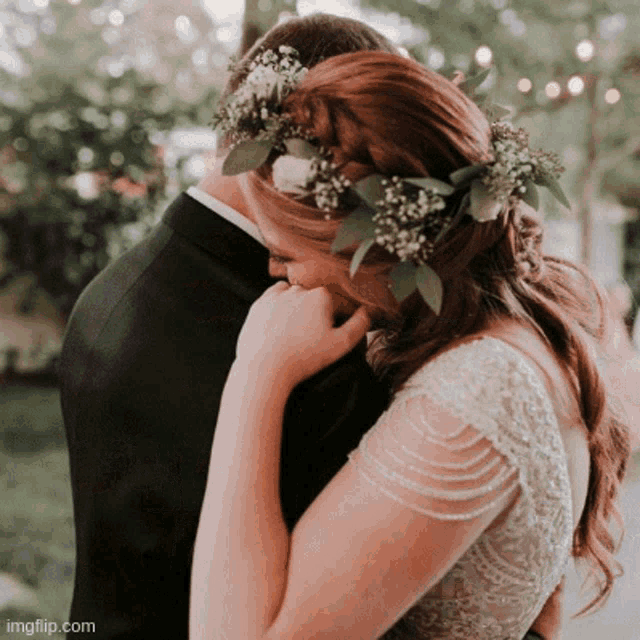 a bride with a flower crown on her head hugging her groom