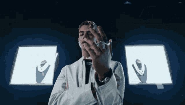 a man in a white jacket holds a ring in front of a display of necklaces