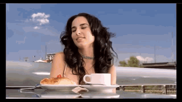 a woman sits at a table with a cup of coffee and a plate of food
