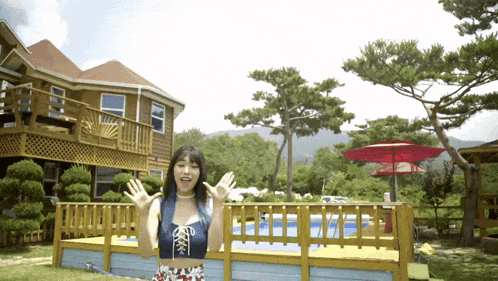 a woman stands in front of a house with a pool in the backyard
