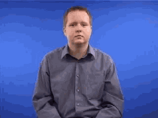 a man in a blue shirt is making a rude gesture with his fingers .