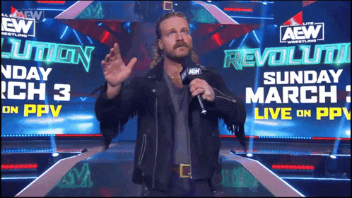 a man stands in front of a sign that says aew