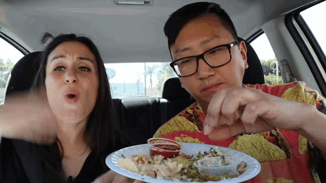 a man in a taco shirt is eating a plate of food next to a woman
