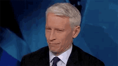 a man in a suit and tie is making a funny face on a television show .