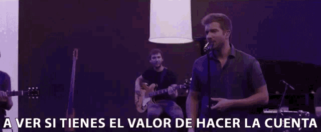 a man singing into a microphone with the words " a ver si tienes el valor de hacer la cuenta " behind him