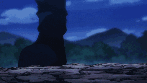 a silhouette of a person standing on a rocky cliff with mountains in the background