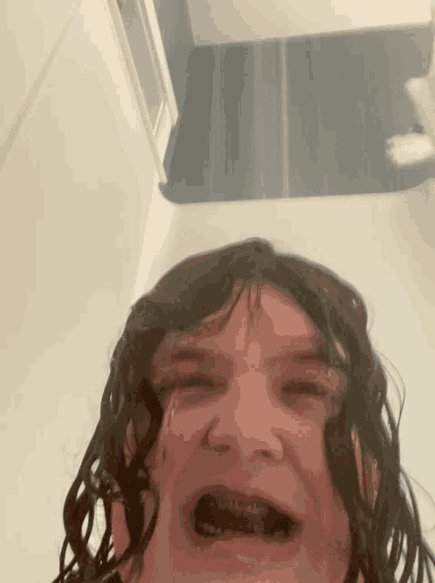 a person with braces on their teeth is crying in a bathroom