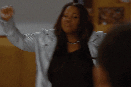 a woman in a white jacket is dancing in front of a man