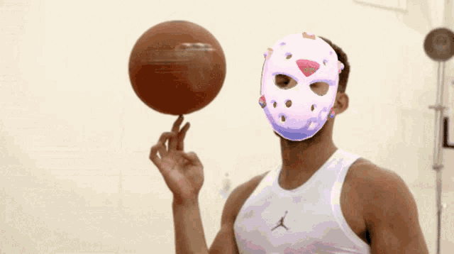 a man wearing a jason voorhees mask holds a basketball in front of his face