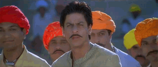 a man with a mustache is standing in a line with other men wearing turbans