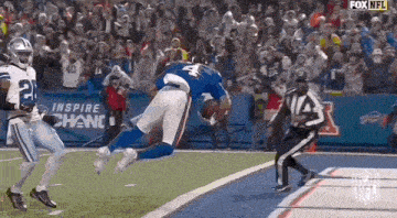 a football player with the number 4 on his jersey is flying through the air while a referee watches .