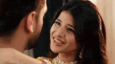 a man and woman are looking at each other and smiling .
