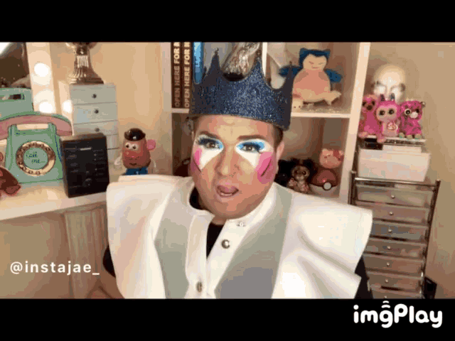 a man with a crown on his head is sitting in front of a shelf with stuffed animals and a green telephone