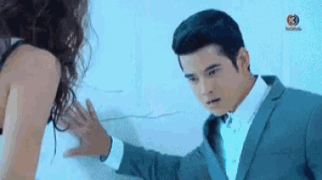 a man in a suit and tie is touching a woman 's shoulder .
