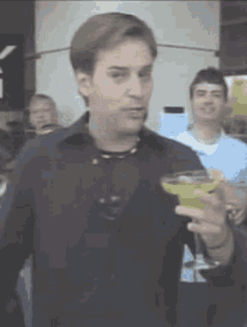 a man in a black shirt is holding a martini in his hand