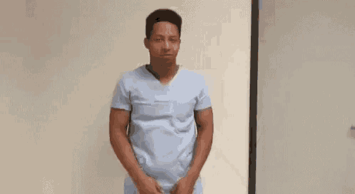 a man in a blue scrub top is dancing in a room .