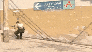 a man is aiming a rifle in front of a sign for hotel aurore
