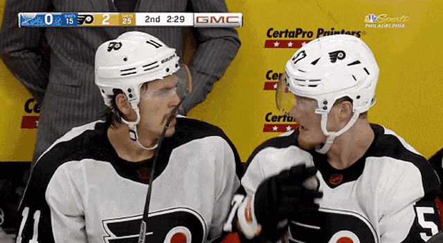 two hockey players looking at each other with gmc on the screen behind them