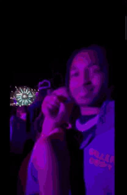 a man and a woman are posing for a picture in a dark room with purple lights .