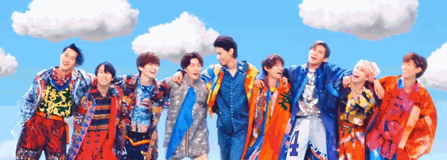 a group of young men are posing for a picture in front of a blue sky with clouds