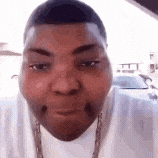 a man is making a funny face while wearing a white shirt and a chain around his neck .