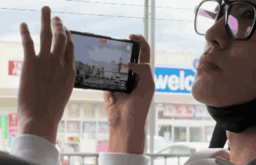 a person taking a picture with their phone in front of a welc store