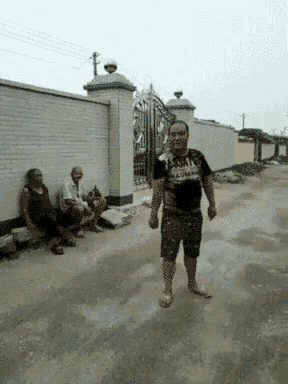 a man wearing a t-shirt that says ' avengers ' on it is walking down a dirt road .