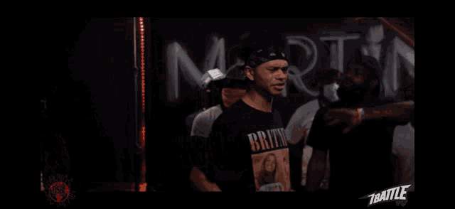 a man wearing a britney spears shirt stands in front of a sign that says mart