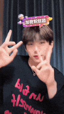 a man wearing a black shirt that says bloom on it is making a peace sign