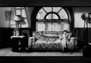 a woman sits on a couch in front of a large window