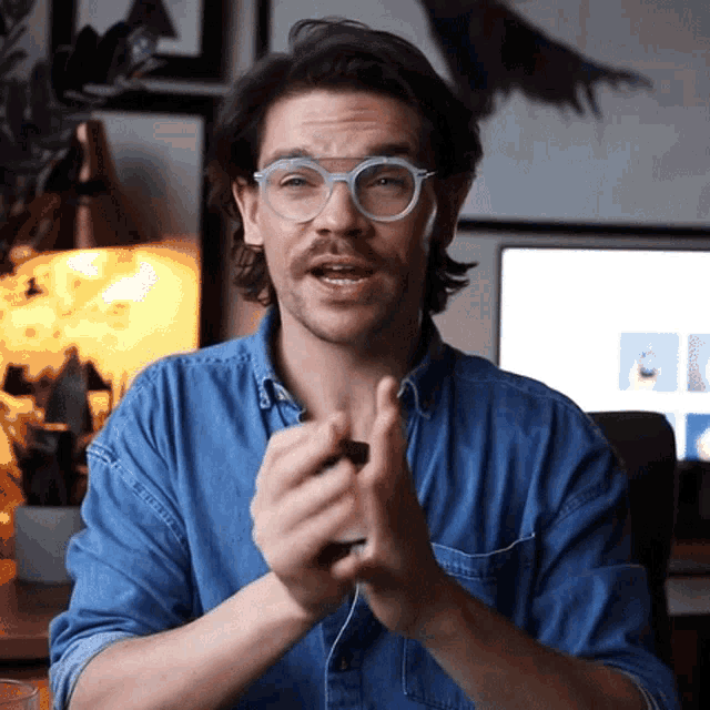 a man wearing glasses and a blue shirt is making a face