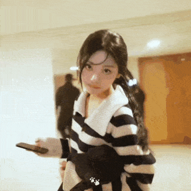 a woman wearing a striped sweater is holding a cell phone .