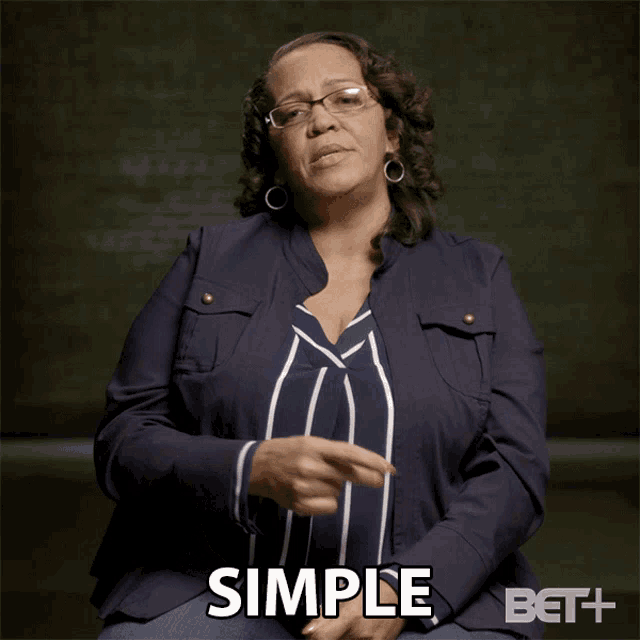 a woman wearing glasses and a blue jacket has the word simple on her chest