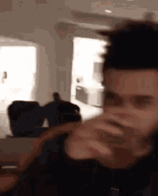 a man is drinking from a glass while sitting in a living room .