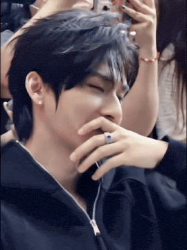 a man with a ring on his finger covers his mouth