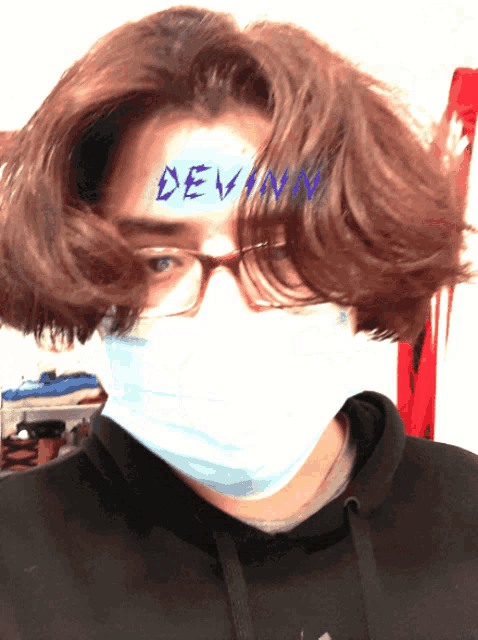 a person wearing a face mask has the name devin written on their forehead