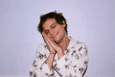 a man with his eyes closed is wearing a white shirt with flowers on it