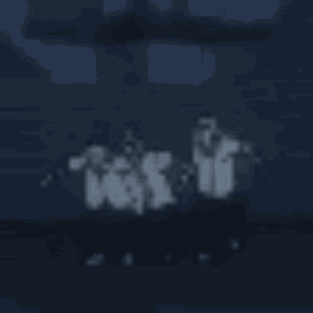 a blurry picture of a group of people standing next to each other in a dark room .