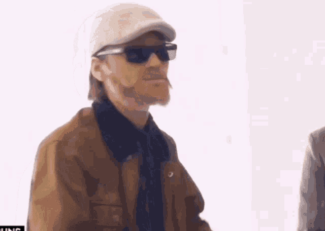 a man wearing sunglasses and a hat is smoking a cigarette ..