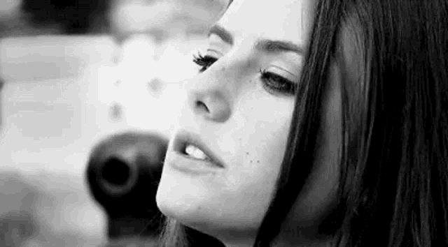a black and white photo of a woman 's face with a serious look on her face .