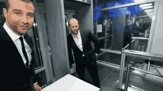 two men in suits and ties are standing next to each other in a building .