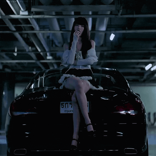a woman sits on the back of a black car with a license plate number 505