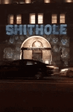 a car is driving past a building that says shithole on it