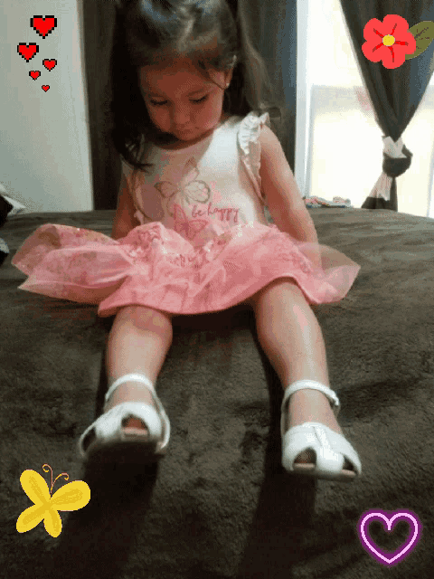 a little girl wearing a pink dress that says happy on it